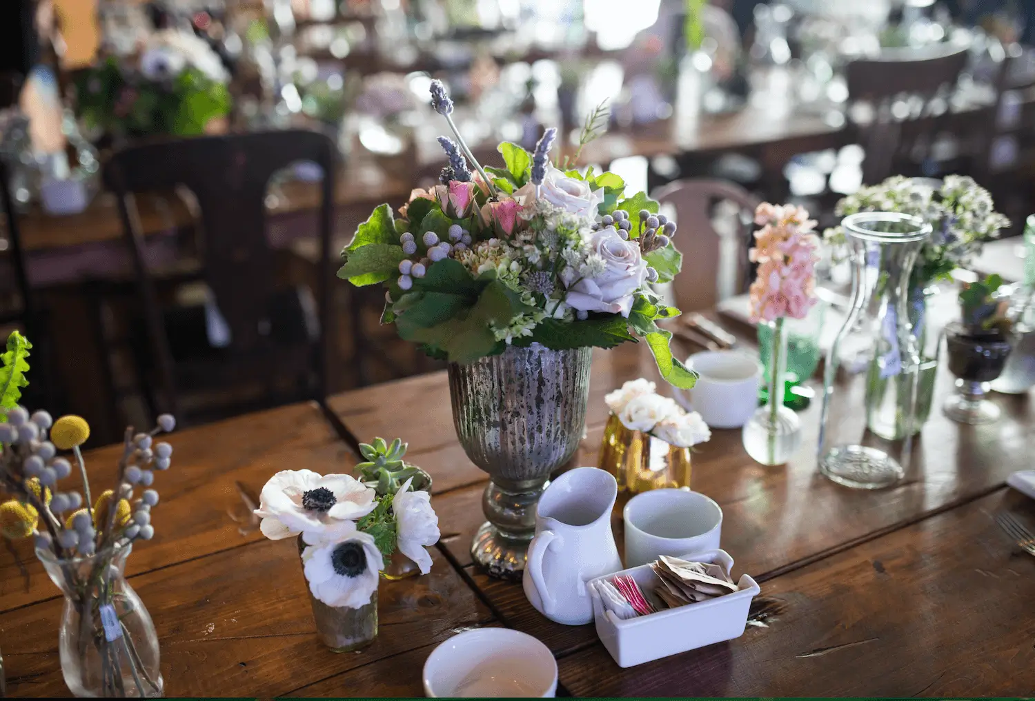 Elegant floral centerpiece with tea set on a wooden table.